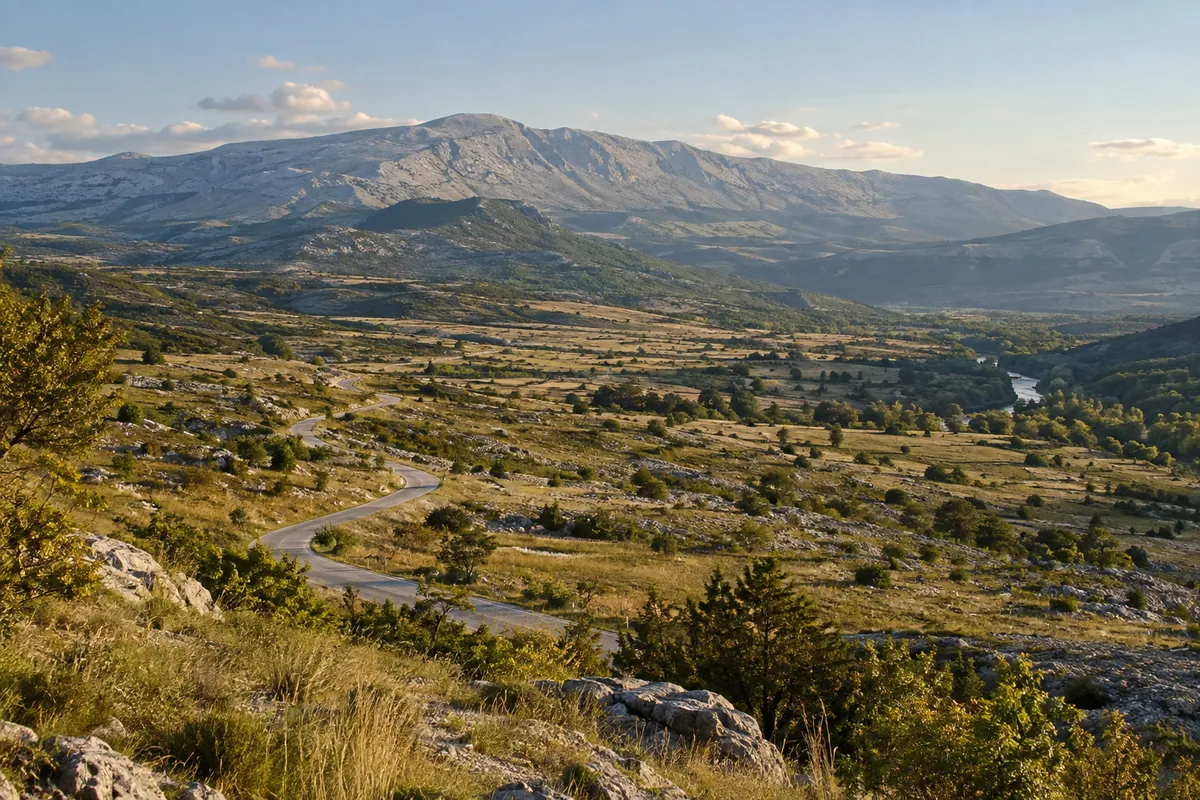 A motorcycle overlooks broad karst country and the pale slopes of Dinara above the upper Cetina.