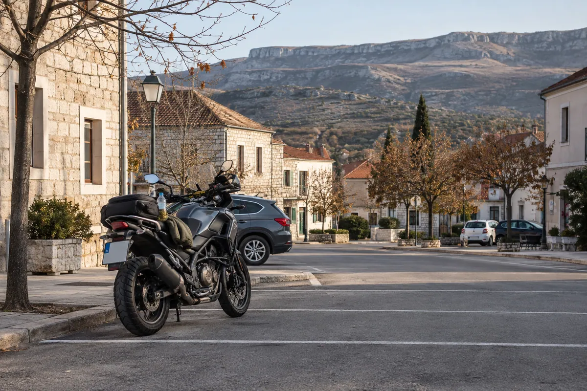 A touring motorcycle is parked in town with water and a layer for changing high-country weather.